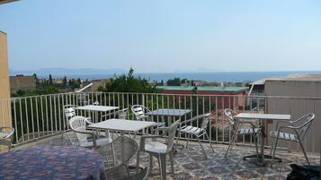 Una terrazza con posti a sedere all'aperto, un pavimento decorato e vista sul mare e edifici in lontananza.