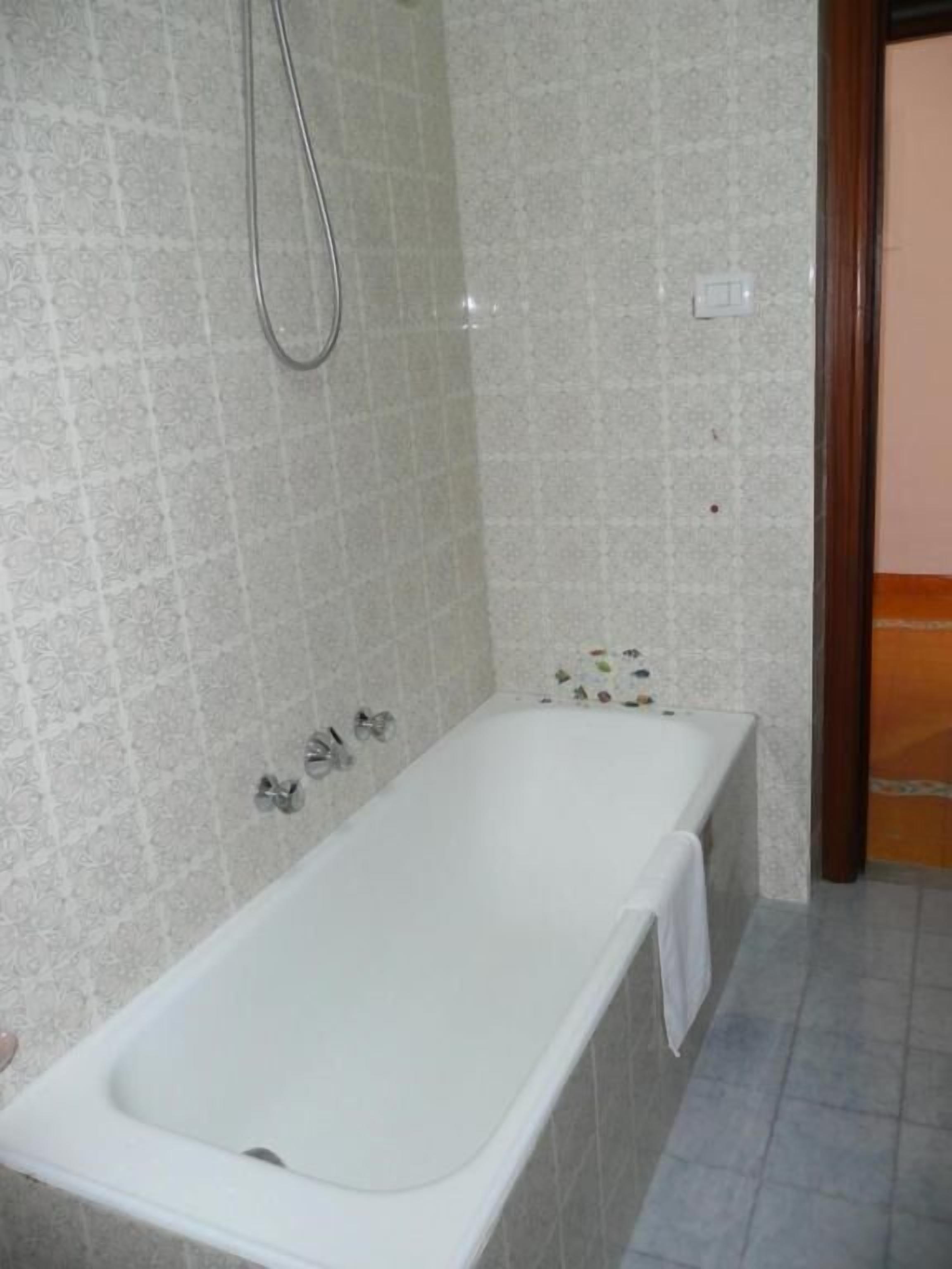 A bathroom with a white bathtub, a shower, and tiled walls.
