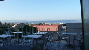 Un balcón con mobiliario exterior y vistas al mar y montañas a lo lejos.