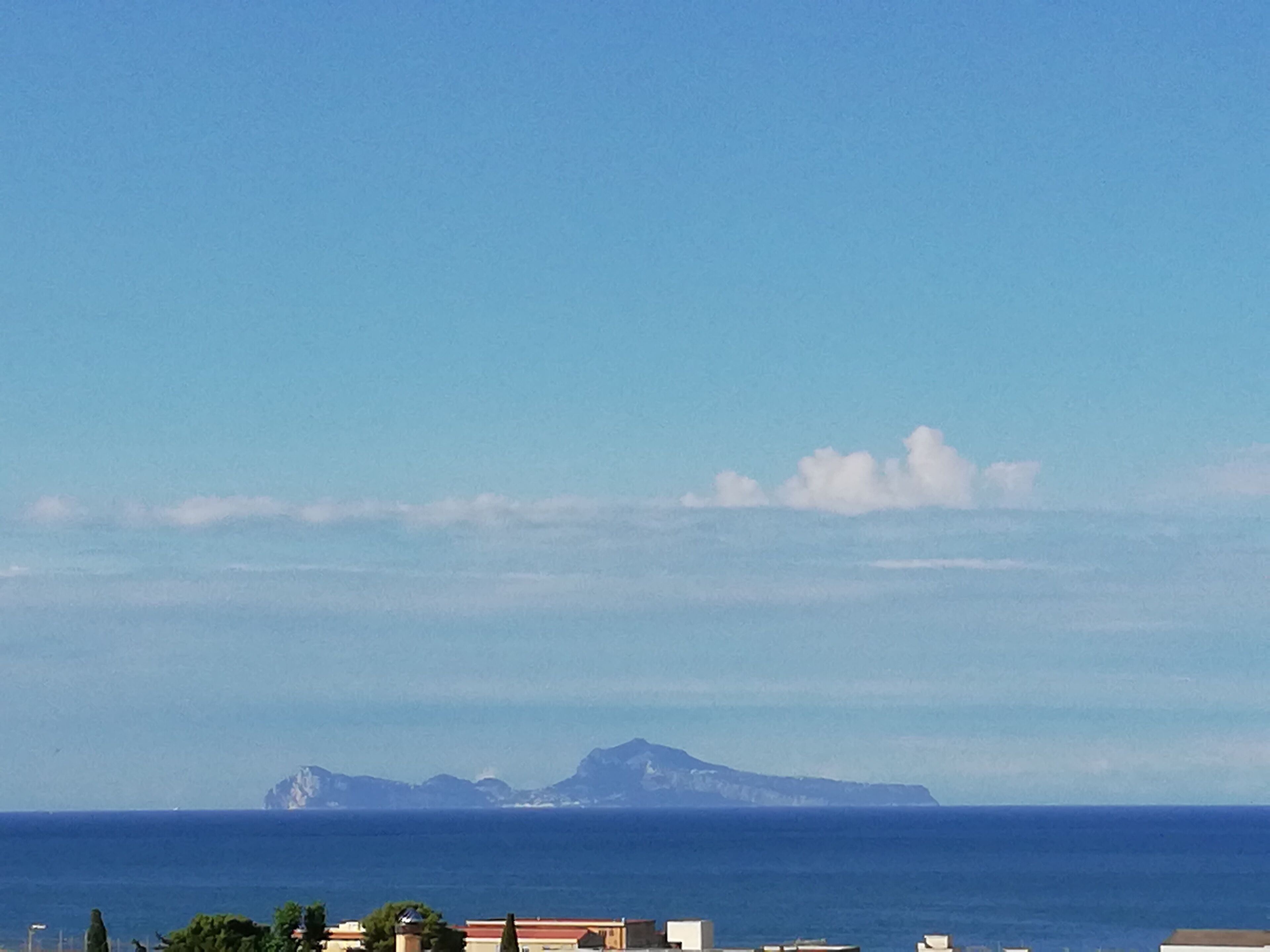 Une vue sur la côte, avec des bâtiments et une montagne en arrière-plan.