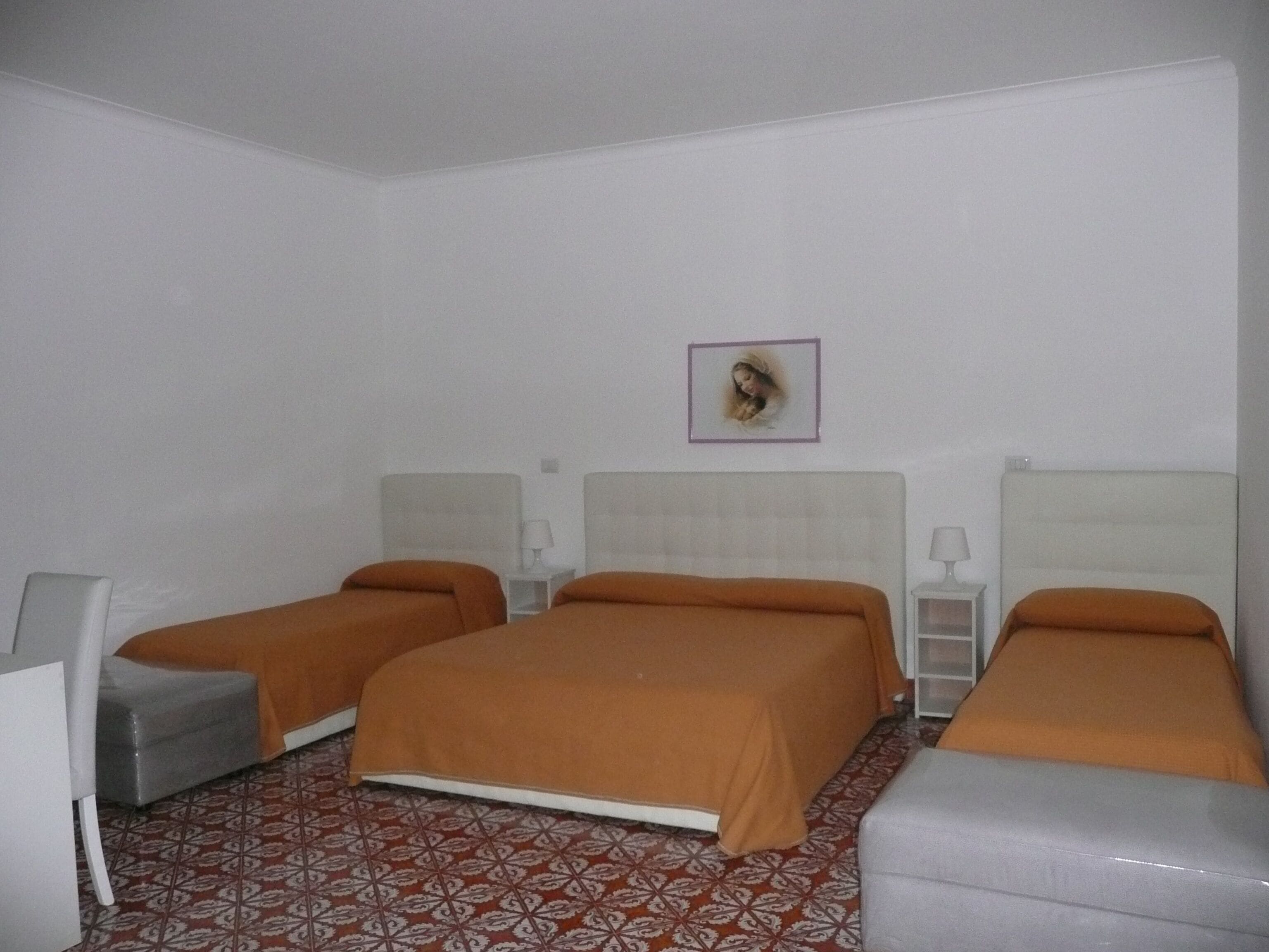 A hotel room with two beds, a small table, a chair, and a patterned floor.