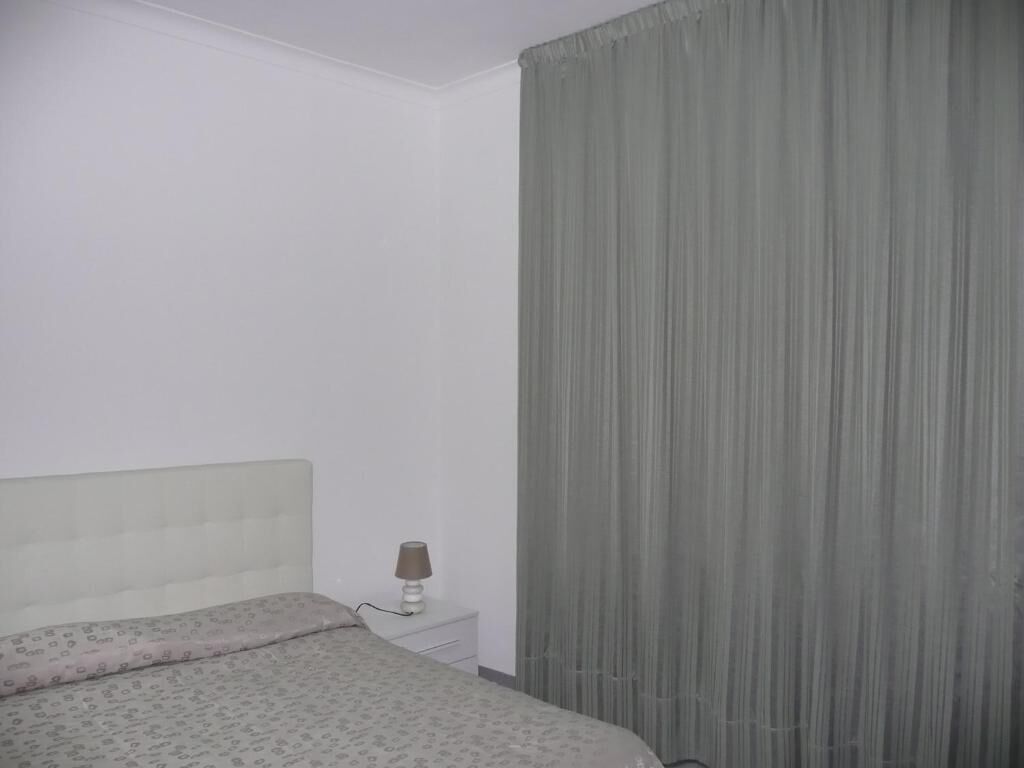Un dormitorio con una cama, una mesita de noche y una lámpara.