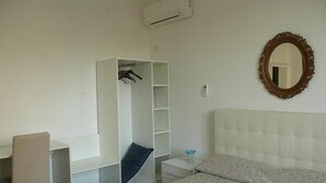 Un dormitorio con cama, armario, escritorio y espejo.