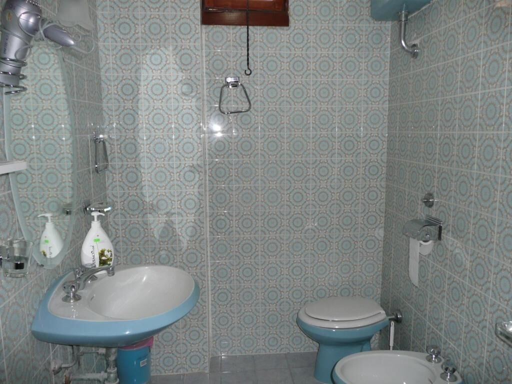 A bathroom with patterned tiles, a sink, a toilet, and a bidet.