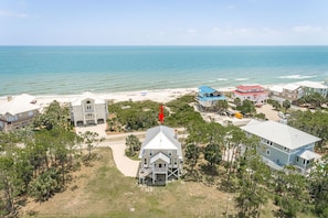 A coastal property with a large house featuring a prominent front porch and multiple windows.