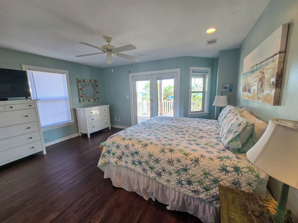A bedroom with a bed, dresser, and ceiling fan.