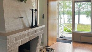 A fireplace with a stone mantle, a black candle holder, and a basket of firewood. - 4 Star Holiday Home in Gislaved (Gislaved)