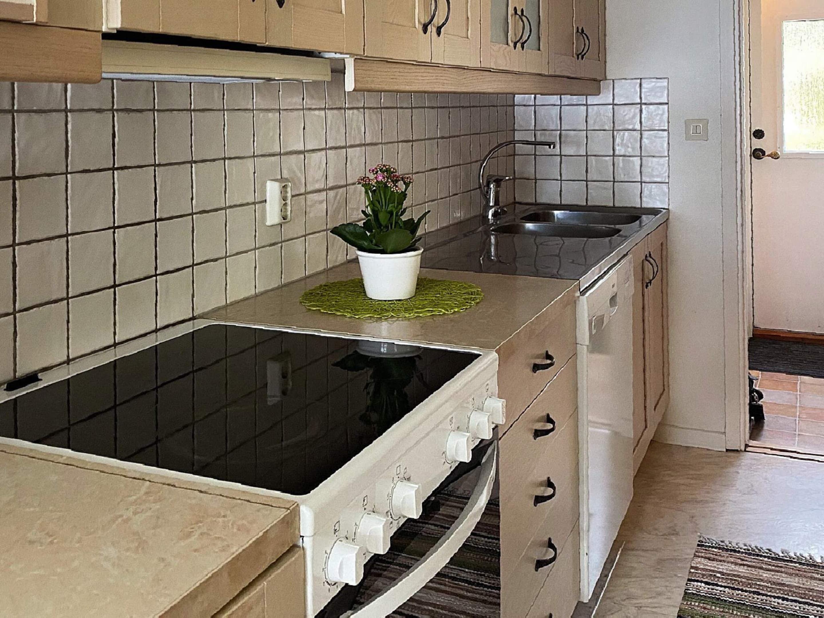 A kitchen with a stove, sink, and cabinets.