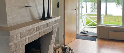 A fireplace with a stone mantle, a black candle holder, and a basket of firewood.