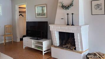 A living room with a fireplace, a television on a white cabinet, and a framed picture on the wall.