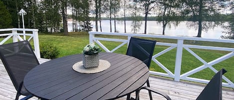 Une terrasse avec une table ronde et des chaises, donnant sur un lac.