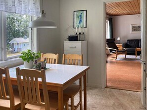 A dining area with a table and chairs, a pendant light, a potted plant, and a view of a house outside. - 4 Person Holiday Home in Gislaved-by Traum (Gislaved)