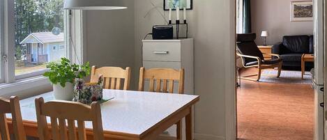A dining area with a table, chairs, a potted plant, and a white lamp.