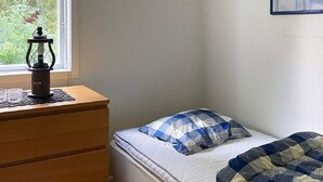 A bedroom with a bed, a wooden dresser, and a window. - 4 Star Holiday Home in Gislaved (Gislaved)