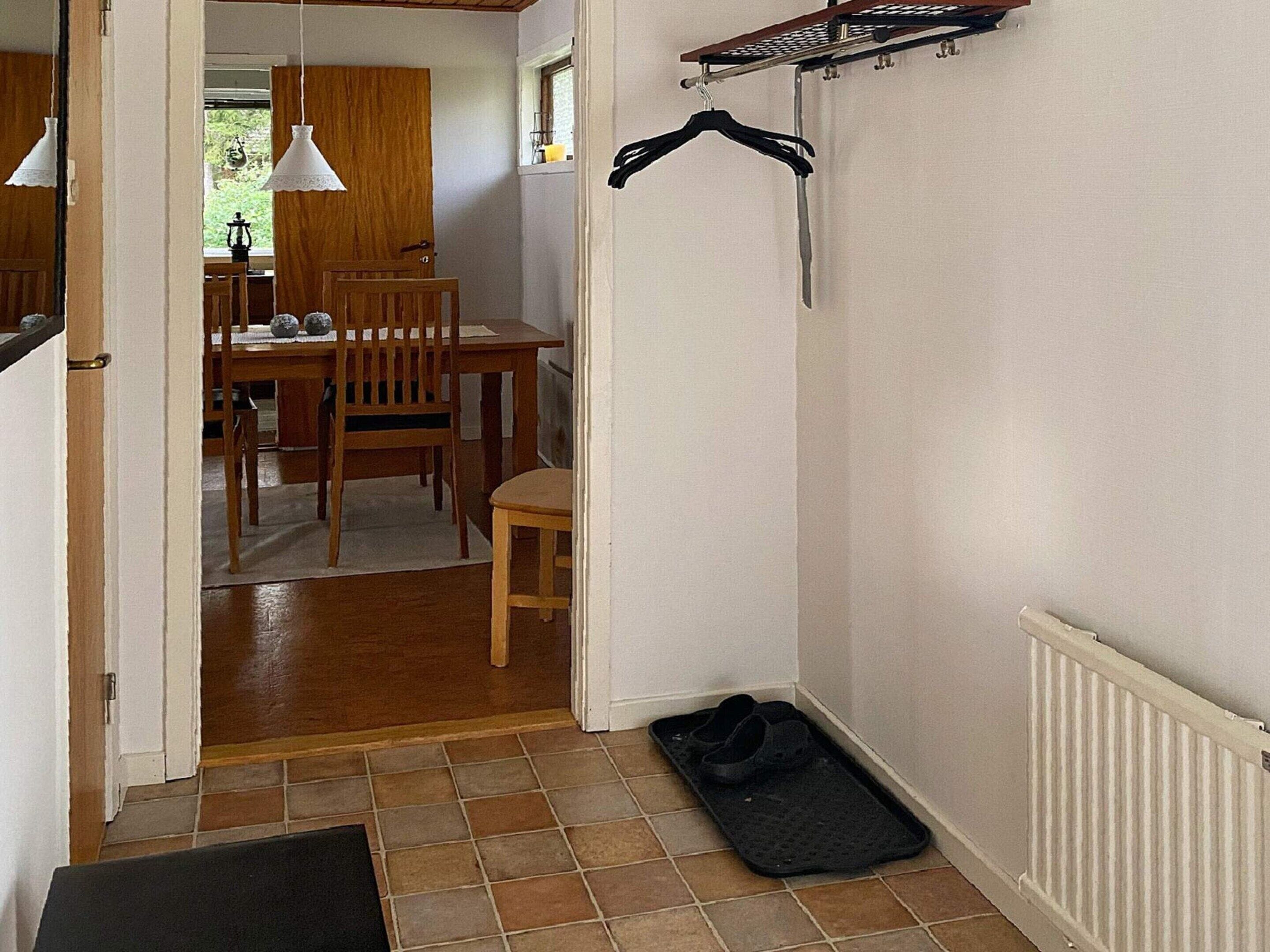 A hallway with a dining area in the background, a radiator, and a black mat on the floor.