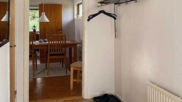 A hallway with a dining area in the background, a radiator, and a black mat on the floor. - 4 Star Holiday Home in Gislaved (Gislaved)