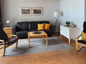 A modern living room with a black leather sofa, wooden coffee table, and a white dresser. - 4 Person Holiday Home in Gislaved-by Traum (Gislaved)