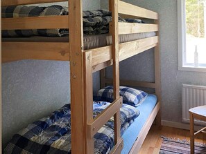A bunk bed with blue and black checkered bedding, a wooden chair, and a window with a view of trees. - 4 Person Holiday Home in Gislaved-by Traum (Gislaved)