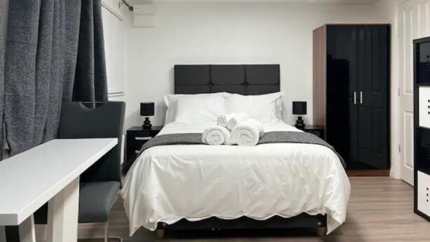 A hotel room with a bed, bedside tables, a desk, and a wardrobe. - Studio Appt - Sleeps 2 - Free Parking - 5min-metro (Manchester)