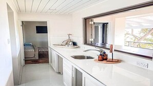 A modern kitchen with white cabinets, a large window, and a view of the outdoors.