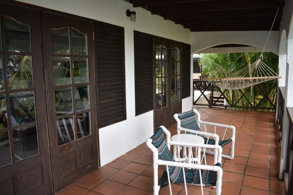 A covered patio with white wicker furniture and a hammock.