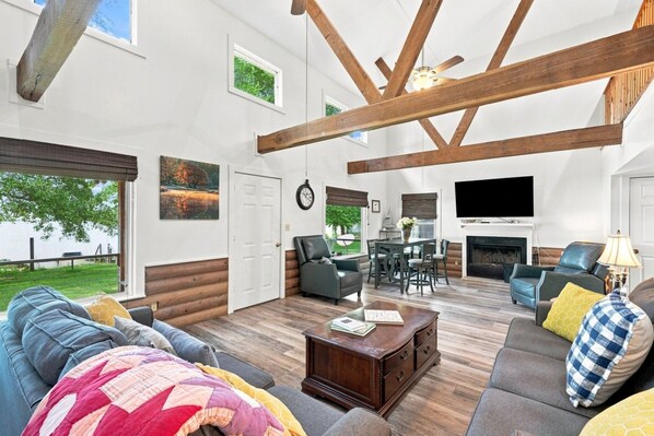 A spacious living room with a fireplace, a dining area, and a view of the outdoors.