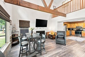 A spacious living room with a fireplace, a dining area, and a kitchen with wooden cabinets.