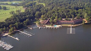 An aerial view of a lakeside property with a dock, a swimming pool, and a building with a red roof.