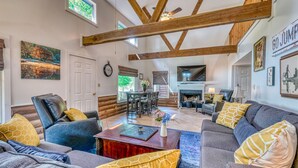 A spacious living room with a fireplace, wooden beams, and comfortable seating.