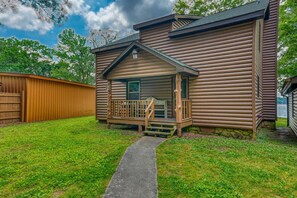 A log cabin with a porch, a stone foundation, and a view of the surrounding area.