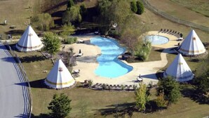 A pool area with three conical structures, surrounded by pathways and greenery.