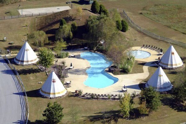 A pool area with three conical structures, surrounded by pathways and greenery.
