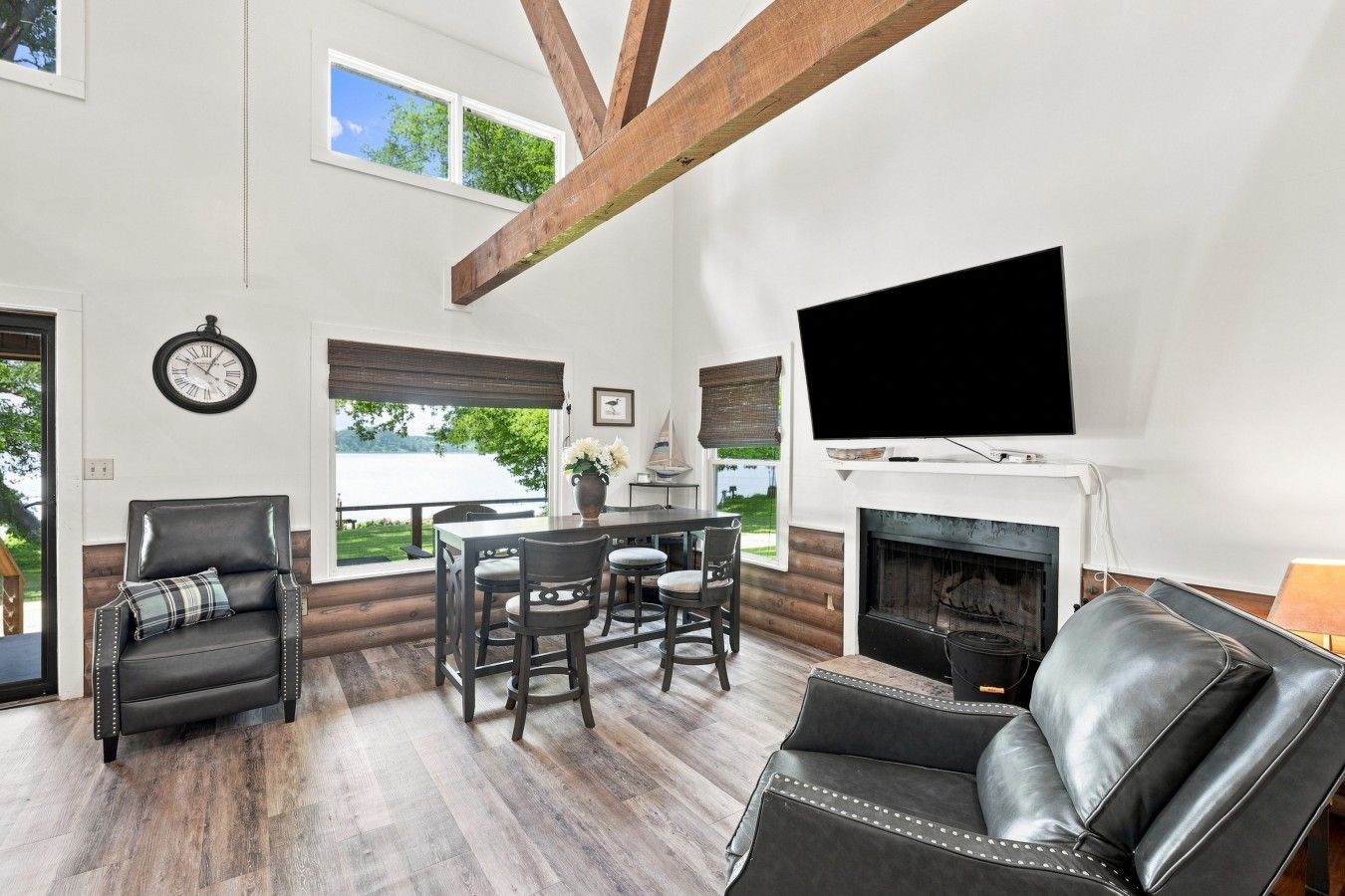 A spacious living room with a fireplace, a television, and a dining area with a view of the outdoors.