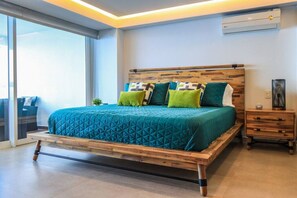 Relax in this serene bedroom with a large bed, nightstand, and potted plant, offering a peaceful retreat.