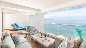 Un balcón con vista al mar, amoblado con un sofá, sillas y una mesa.