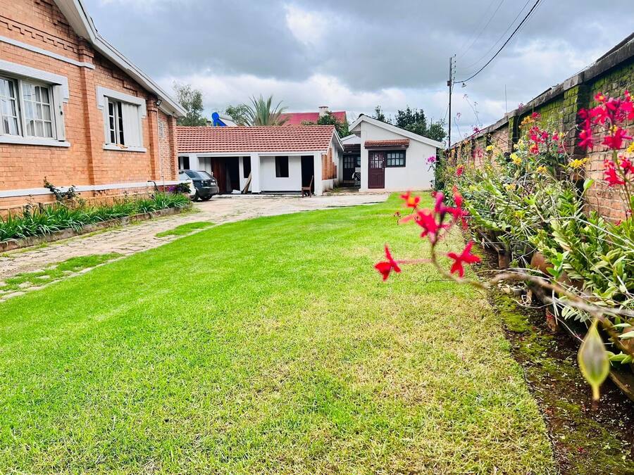 Um imóvel residencial com gramado bem cuidado, casa de tijolos e jardim com plantas floridas.