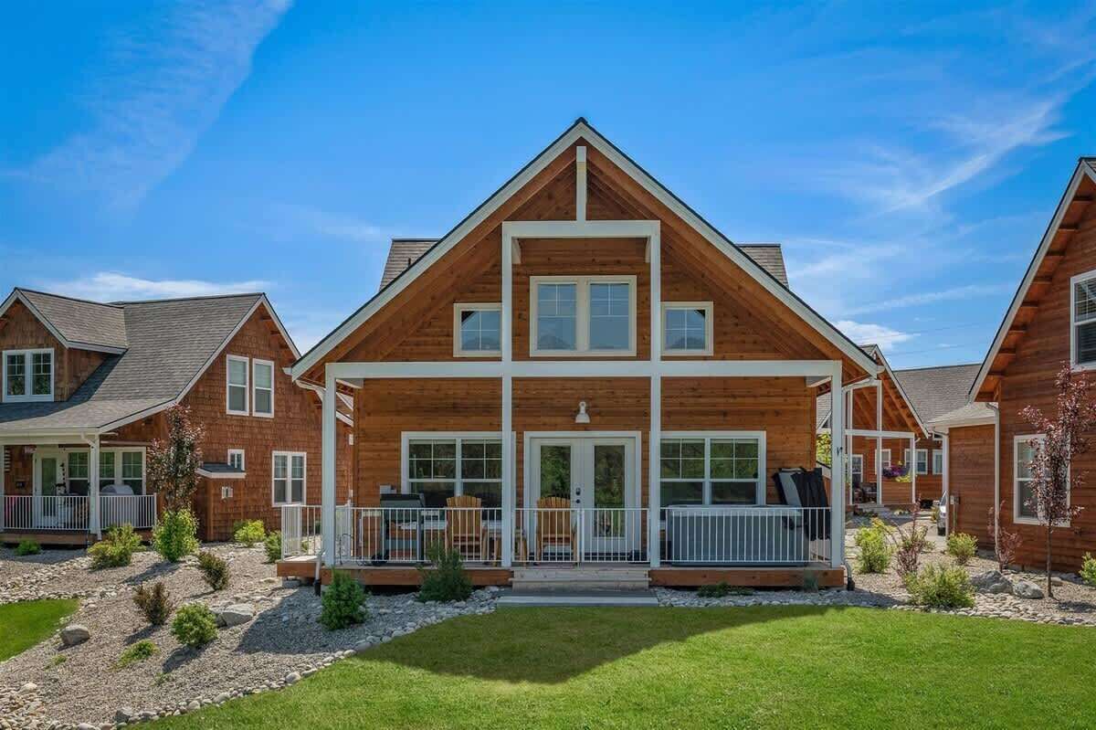A modern log cabin with a central entrance, a covered porch, and a well-maintained lawn.