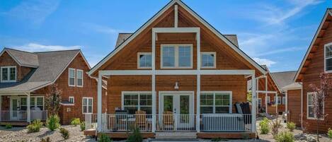 A modern log cabin with a central entrance, a covered porch, and a well-maintained lawn.
