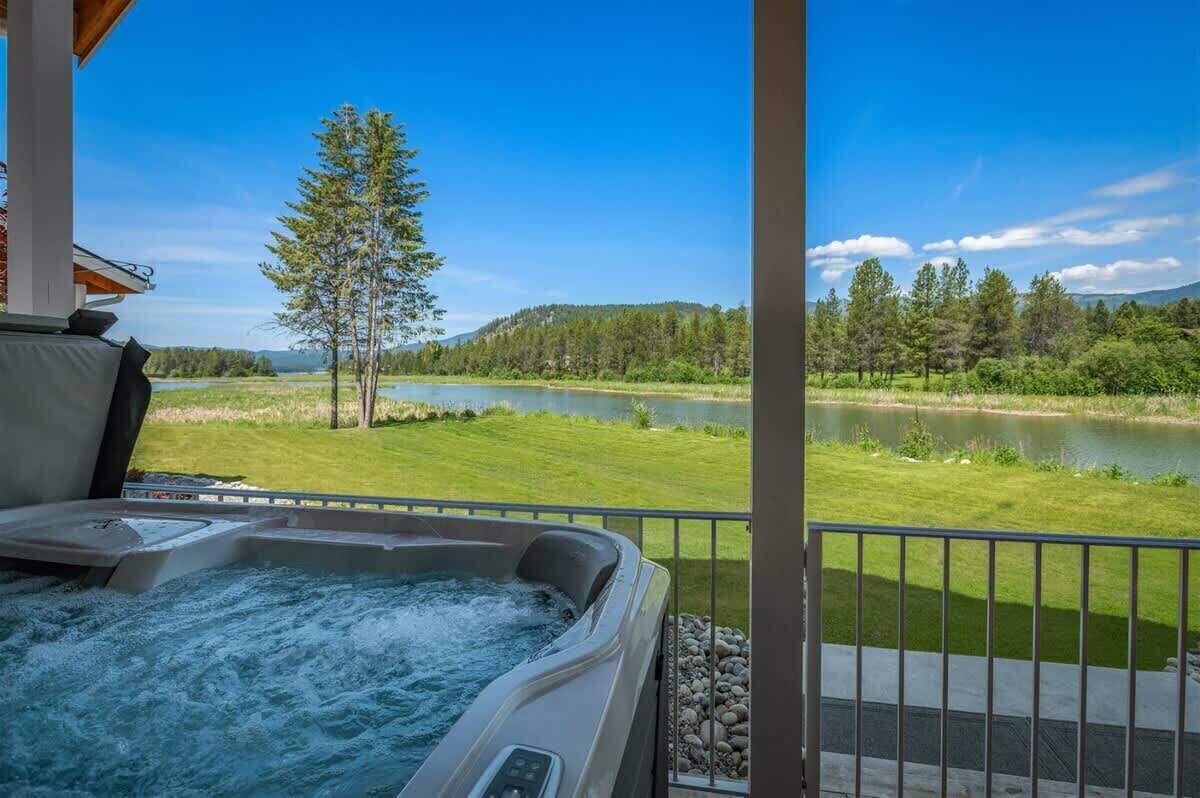 Un jacuzzi en un balcón con vistas a un lago y un bosque.