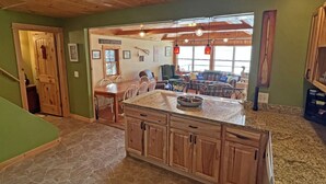 A spacious kitchen with a large island, wooden cabinets, and a stone floor.