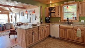 A kitchen with wooden cabinets, a granite countertop, and a built-in dishwasher.
