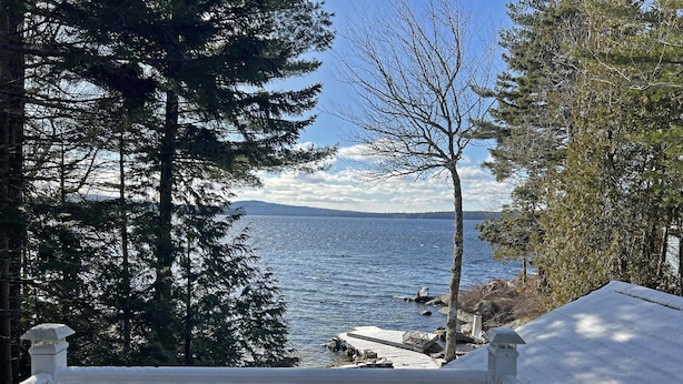 A snow-covered deck with a view of a lake and distant mountains.