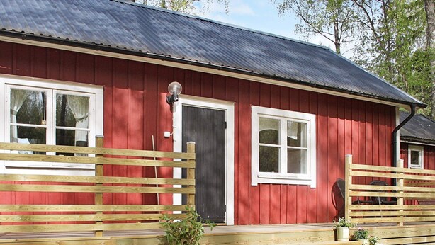 A red wooden building with a dark roof, white-framed windows, and a wooden fence. - 7 Person Holiday Home in Skyllberg (Skyllberg)