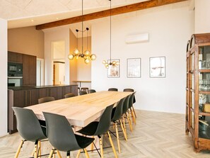 Ein Essbereich mit Holztisch und -stühlen, eine Küche im Hintergrund und eine Holzschrank mit Glastüren.
