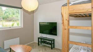 A room with a bunk bed, a television on a stand, a table, and a window with a view of greenery. - 5 Star Holiday Home in Millinge (Millinge)