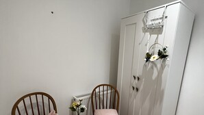 A room with two wooden chairs, a small round table with a vase, and a white wardrobe with heart-shaped hooks. - cosy and clean room- 2 minuets away from train station (London)