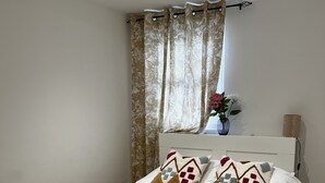 A neatly made bed with white linens, a teal throw blanket, and two folded towels. - cosy and clean room- 2 minuets away from train station (London)