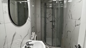 A bathroom with a sink, mirror, toilet, and glass-enclosed shower. - cosy and clean room- 2 minuets away from train station (London)