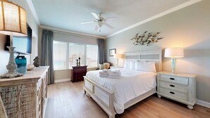 A hotel room with a bed, bedside tables, a ceiling fan, a window with blinds, and a decorative wall piece. - Tops'l Summit 913 Great pool, hot tub, close to beach, private resort (Miramar Beach)