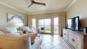 A hotel room with a sofa, armchair, TV, and a balcony with curtains. - Tops'l Summit 913 Great pool, hot tub, close to beach, private resort (Miramar Beach)